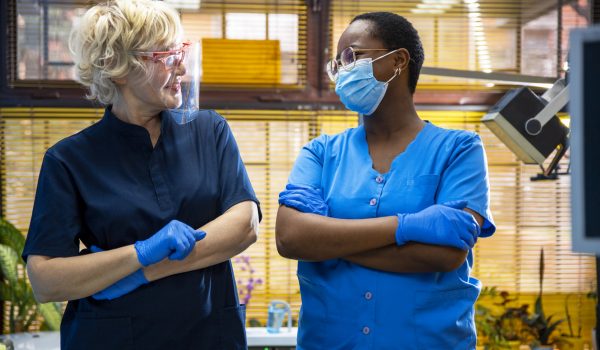 Multiethnic female doctors with face protective mask and blue uniform in medical clinic. Confident diverse age Women paramedics in hospital.